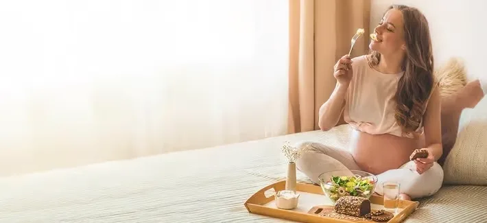 Eine frau, die auf einem bett mit einem tablett essen.