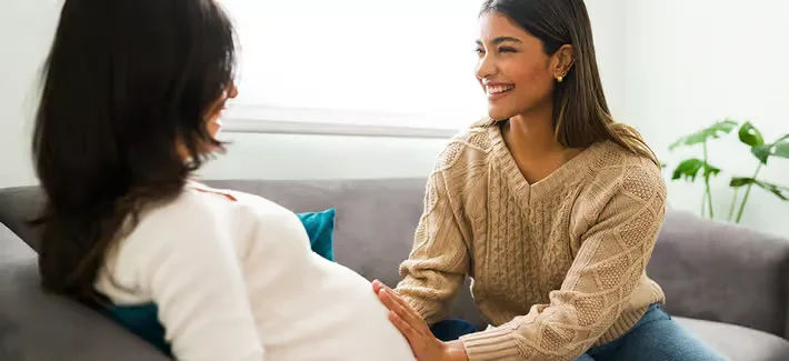 Zwei frauen, die auf einer couch sitzen gemeinsam und miteinander sprechen.