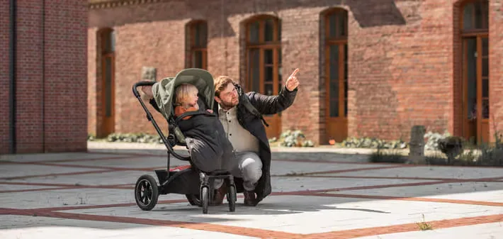 Eine frau, die ein baby in einen kinderwagen schiebt.