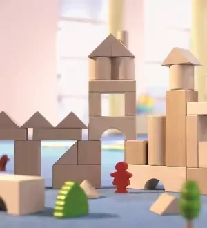Eine detailreiche Burg-Konstruktion aus naturbelassenen Holzbausteinen steht auf einer blauen Spielfläche.