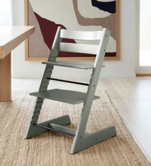 Ein klassischer Treppenhochstuhl aus Holz steht an einem Esstisch.