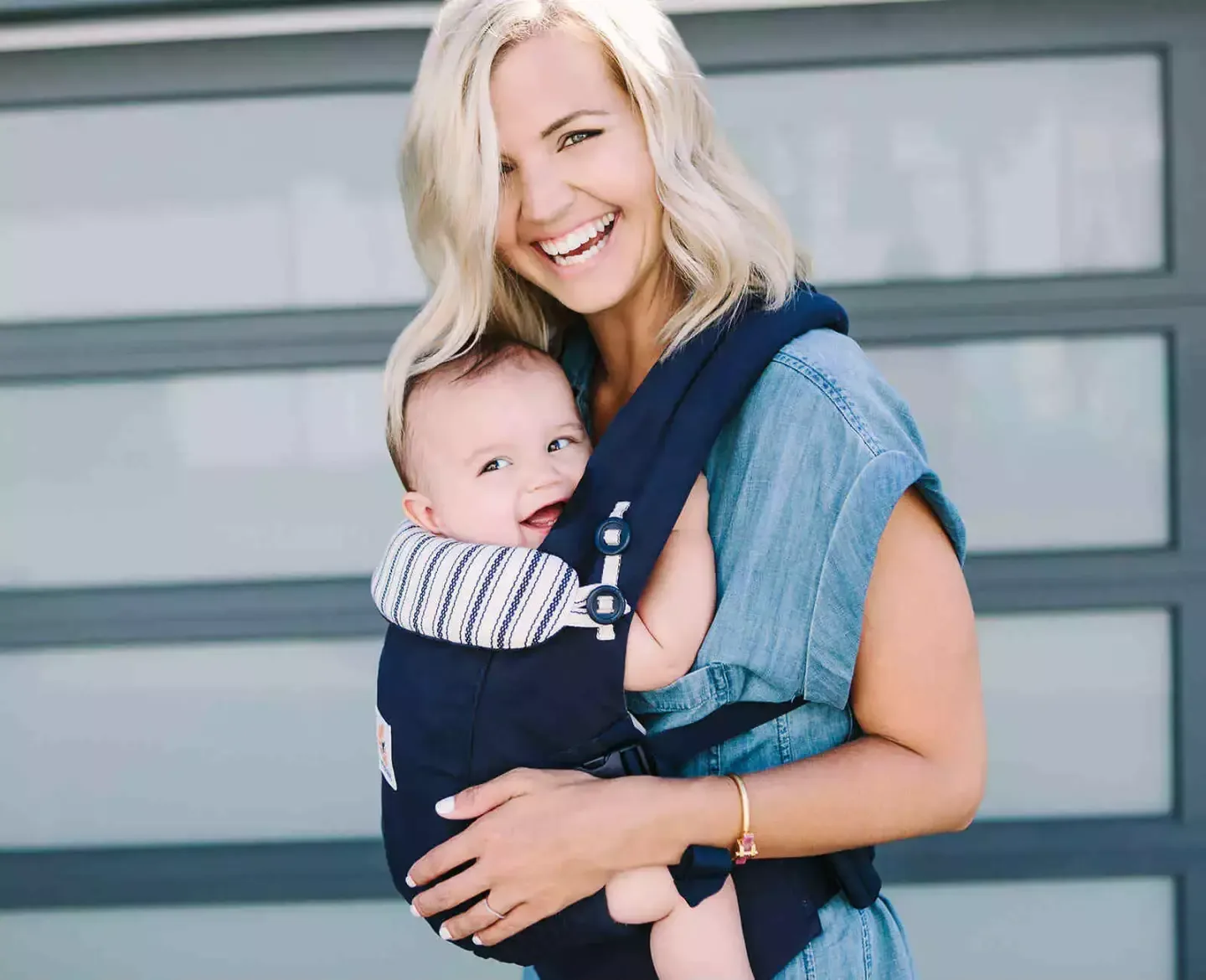 Eine frau, die ein baby in einem babyträger hält.