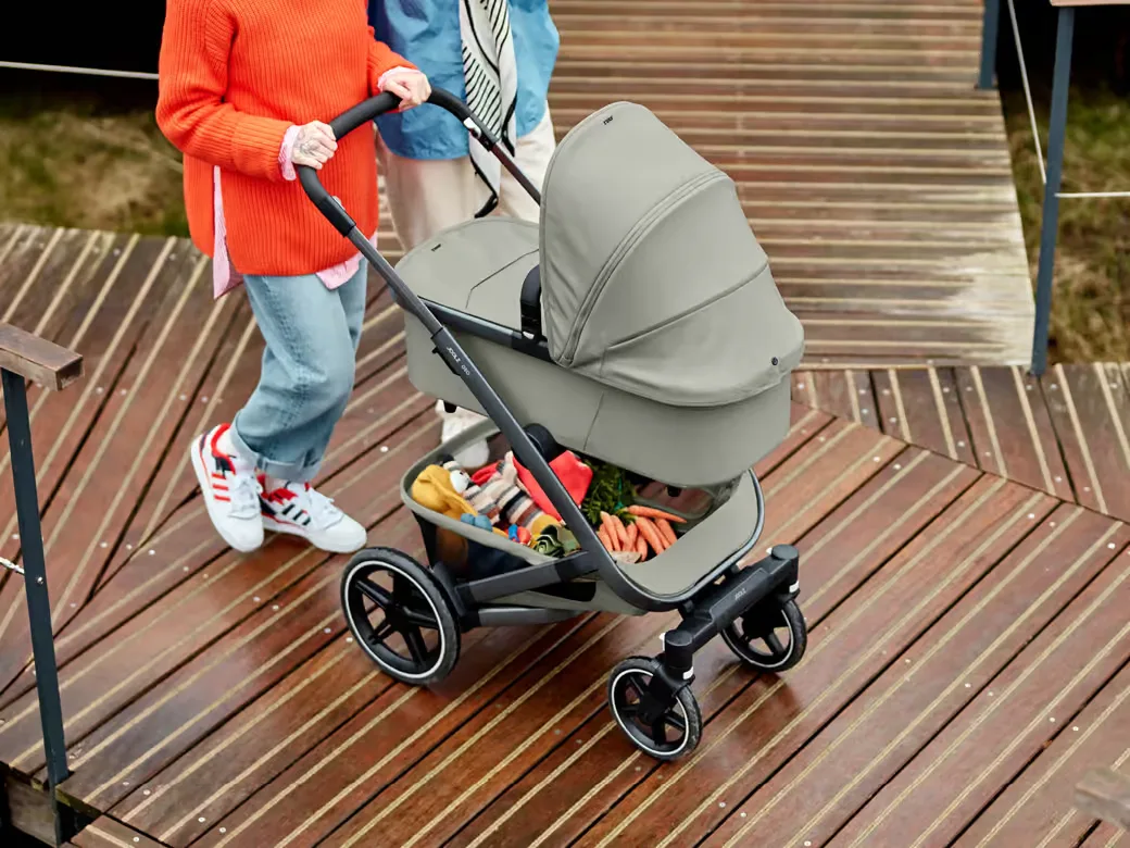 Paar schiebt den Kinderwagen Geo3 in grau von Joolz über einen Holzsteg.