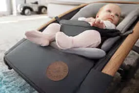 Baby ein, das in einem babysitz in einem wohnzimmer liegt.