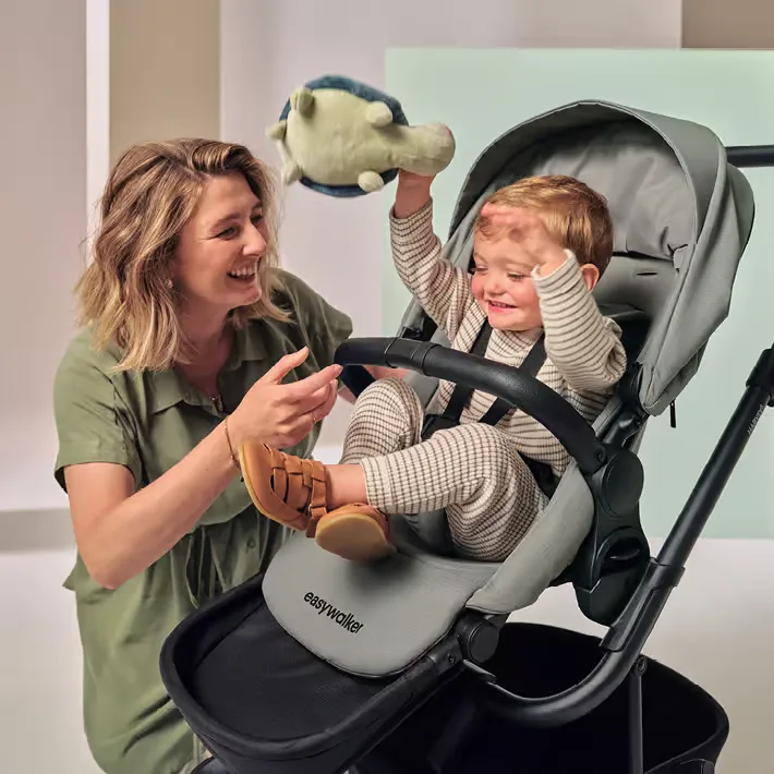 Eine frau, die ein baby in einem kinderwagen hält.