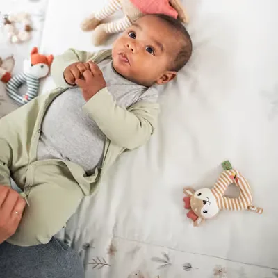 Baby ein, das auf einem bett mit ausgestopften tieren liegt.