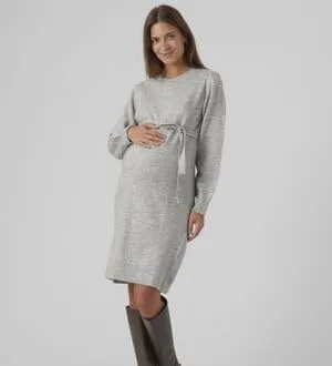 Eine schwangere Frau präsentiert ein knielanges, Strickkleid mit Bindegürtel.