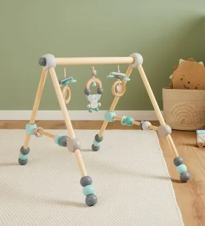 Ein klassischer Spielbogen aus hellem Holz mit hängenden Greiflingen steht auf einer weichen Spielmatte.