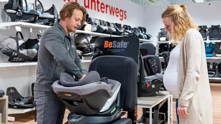 Ein mann und eine frau, die auf einen baby-autositz schauen.