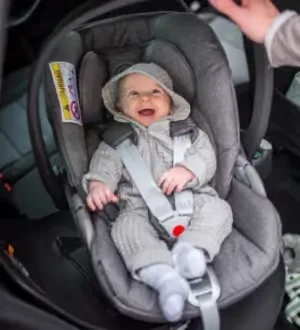 Lachendes Baby in einer Babyschale im Auto