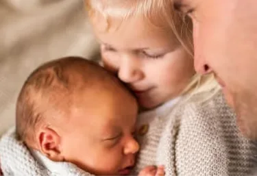 Ein mann, der ein baby in seinen armen hält.