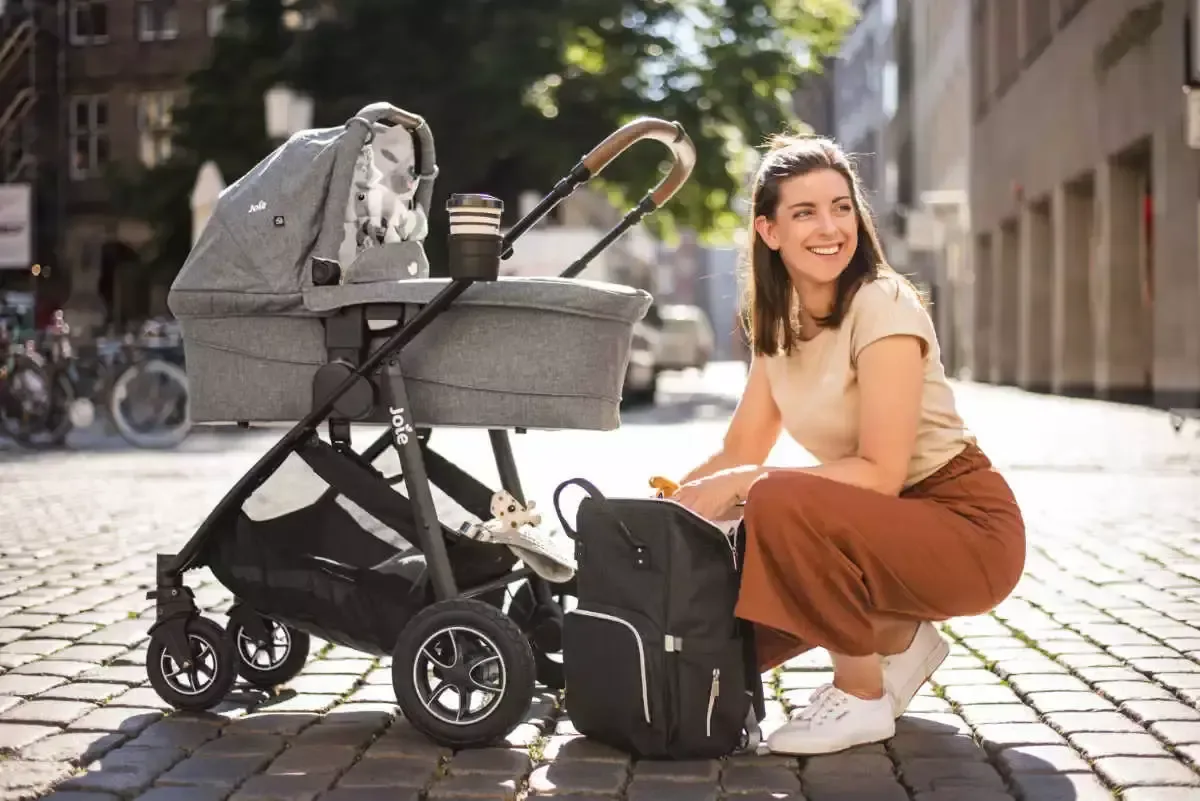 Eine frau, die auf dem boden neben einem kinderwagen sitzt.