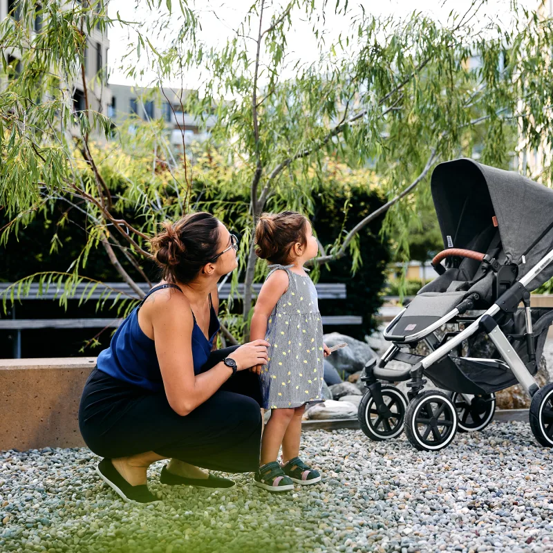 Eine frau kniet sich neben eine baby-kutsche.