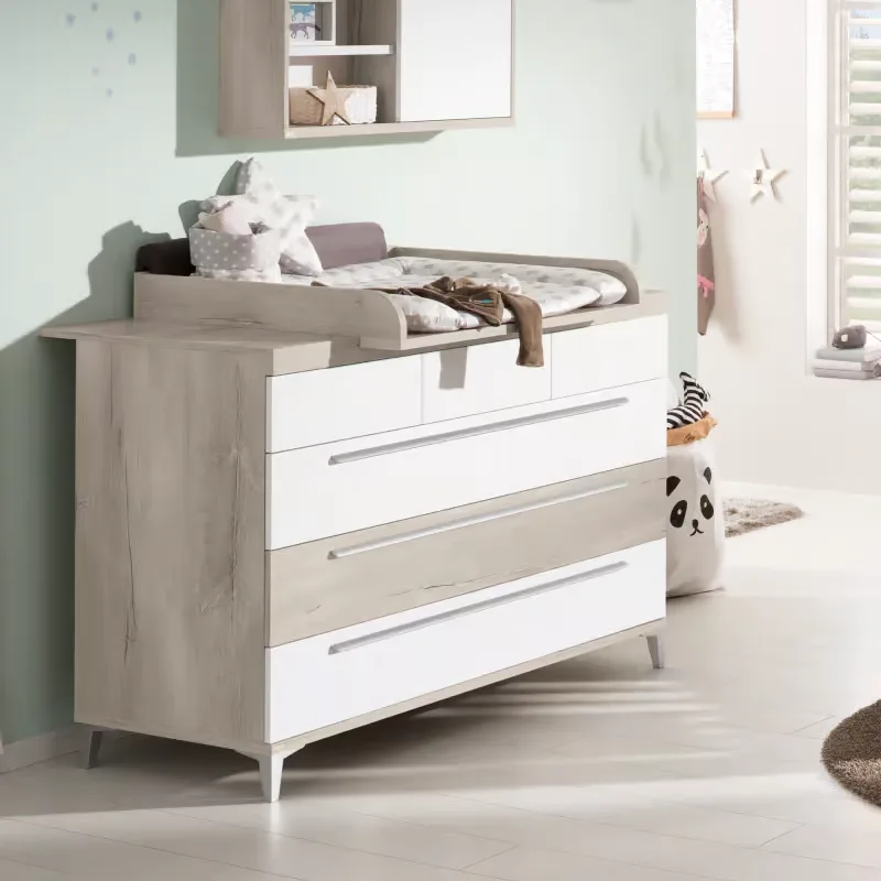 Babyzimmer ein mit einer weißen kommode und einem teddybär.