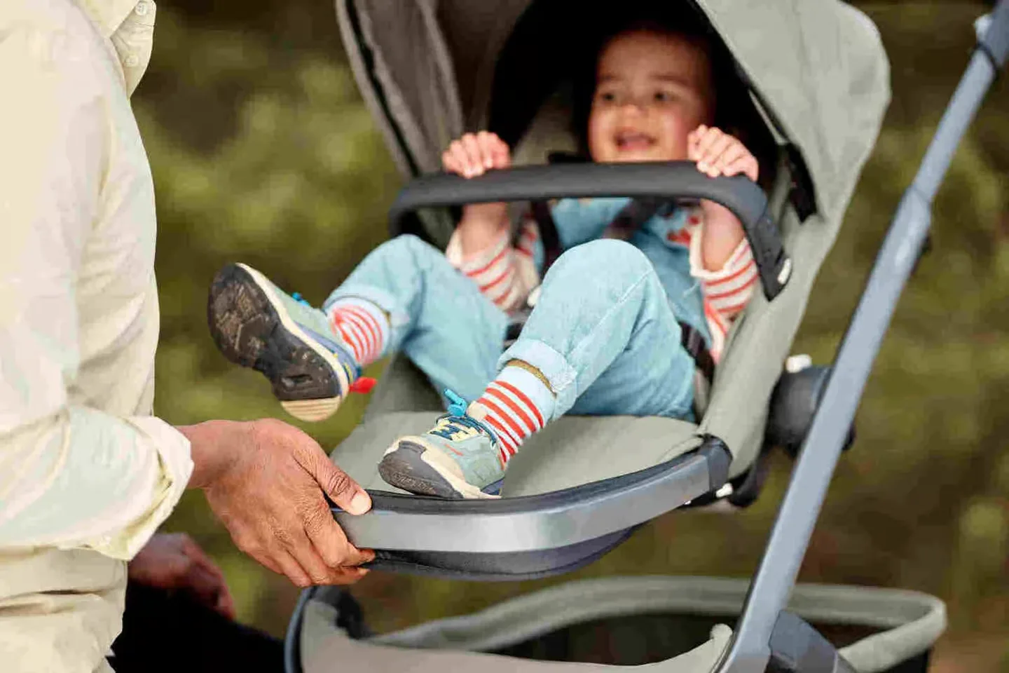 Ein mann, der ein baby in einem kinderwagen hält.