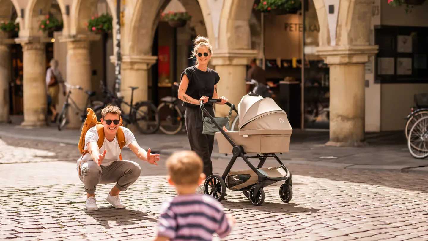 Eine frau, die ein baby in einen kinderwagen schiebt.