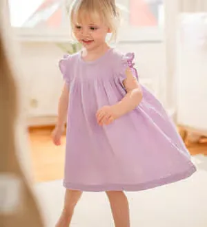 Ein kleines Mädchen trägt ein schönes Kleid aus Musselin-Stoff.