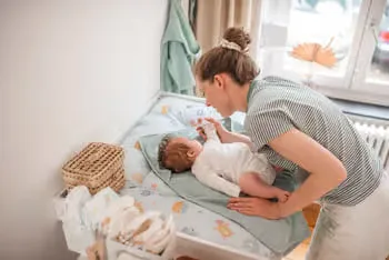 Eine frau, die ein baby in einer krippe hält.