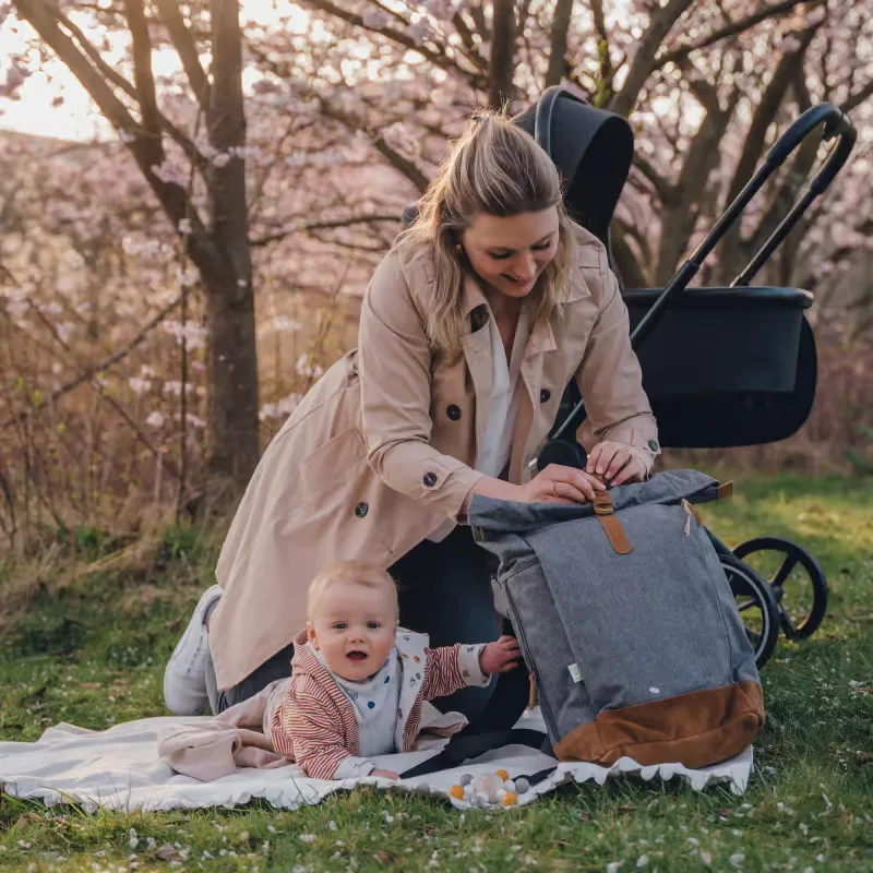 Eine frau, die auf einer decke neben einem baby sitzt.