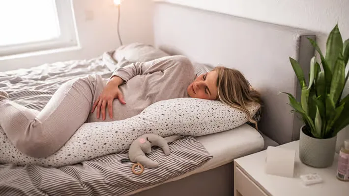 Eine frau, die auf einem bett mit einem kissen liegt.