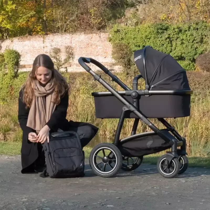 Eine frau, die auf dem boden neben einem kinderwagen sitzt.