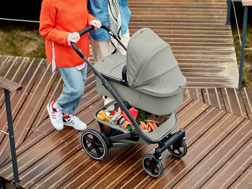 Paar schiebt den Kinderwagen Geo3 in grau von Joolz über einen Holzsteg.