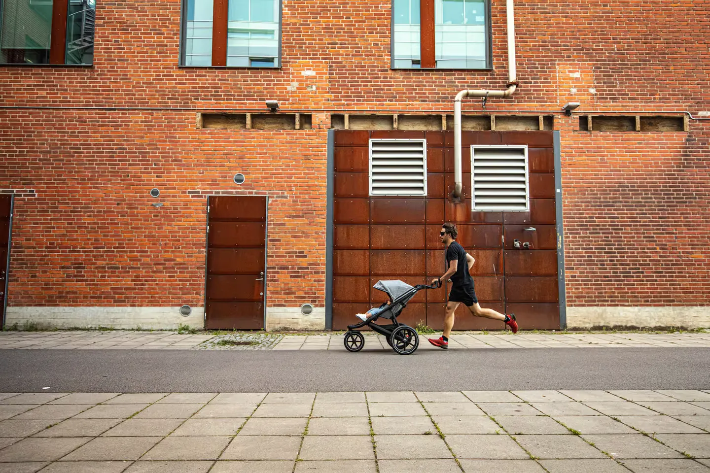 Ein mann, der ein baby in einen kinderwagen schiebt.