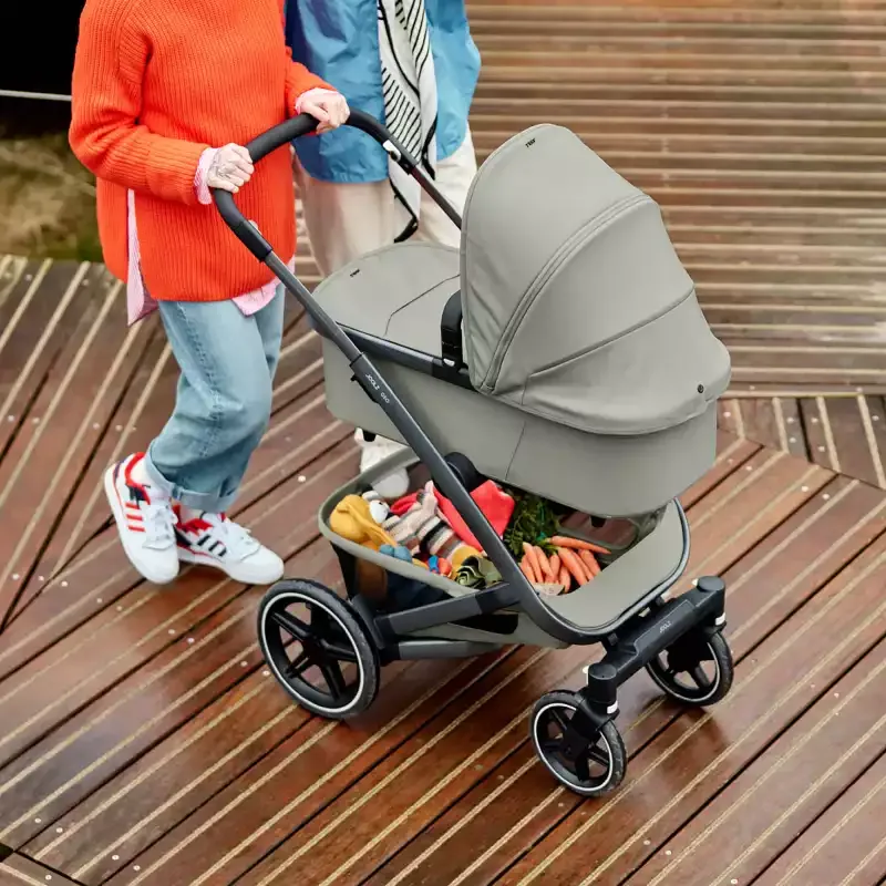 Eine frau, die einen kinderwagen auf ein holzdeck schiebt.