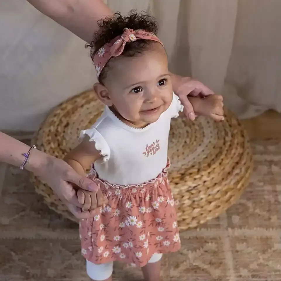 Baby ein mädchen trägt ein weißes hemd und rosa blumenrock.