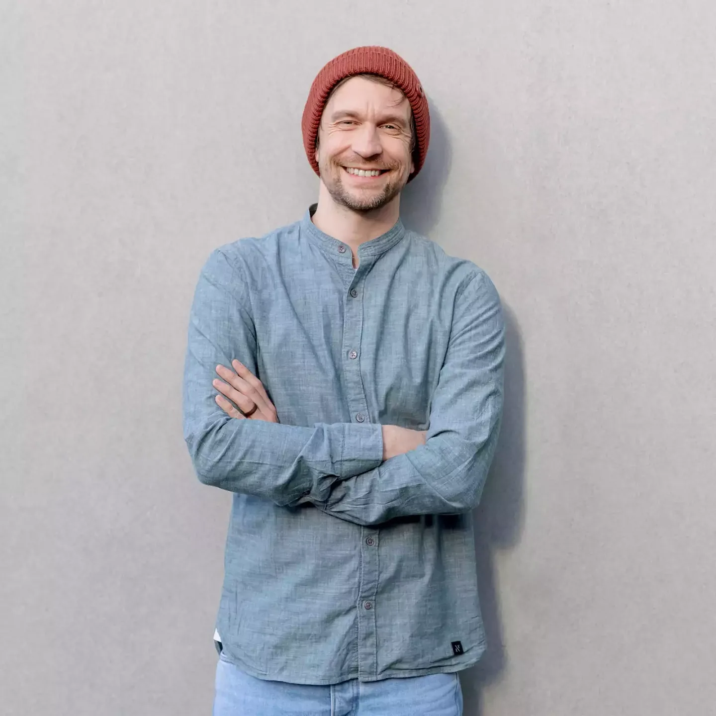 Ein mann trägt ein blaues hemd und einen roten hut.