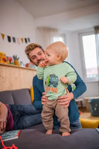 Ein mann, der ein baby in seinen armen hält.