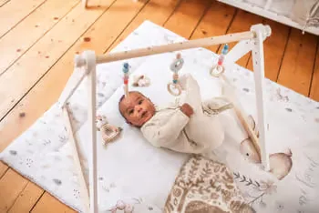 Baby ein, das in einer krippe auf einem holzboden liegt.