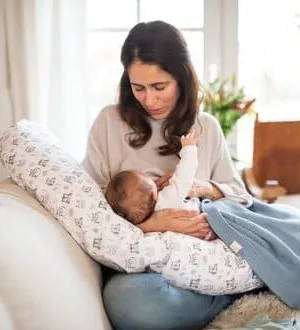 Eine Mutter hält ihr Neugeborenes während des Stillens geborgen in einem Stillkissen.