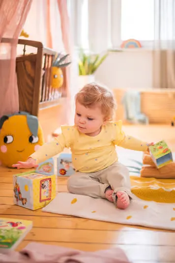 Baby ein, das auf dem boden sitzt und mit spielzeug.
