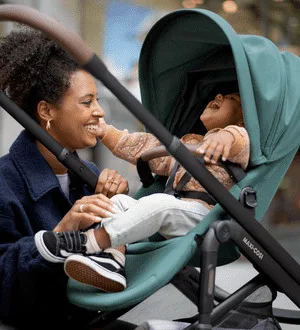 Ein lachendes Kleinkind sitzt in einem Buggy.