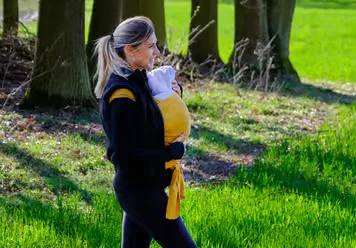 Eine frau, die mit ihrem baby im park spazieren geht.